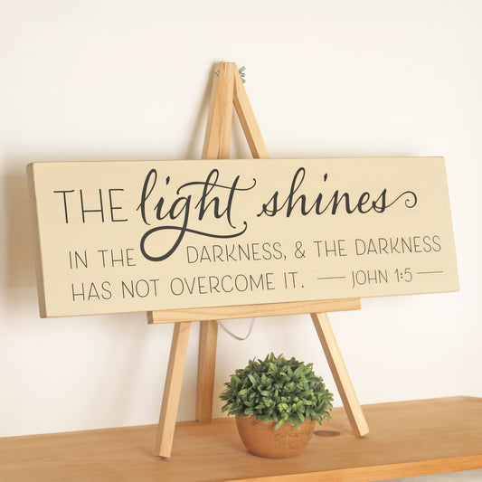The light shines in the darkness and the darkness has not overcome it.  John 1:5, Rustic Wooden Scripture Sign